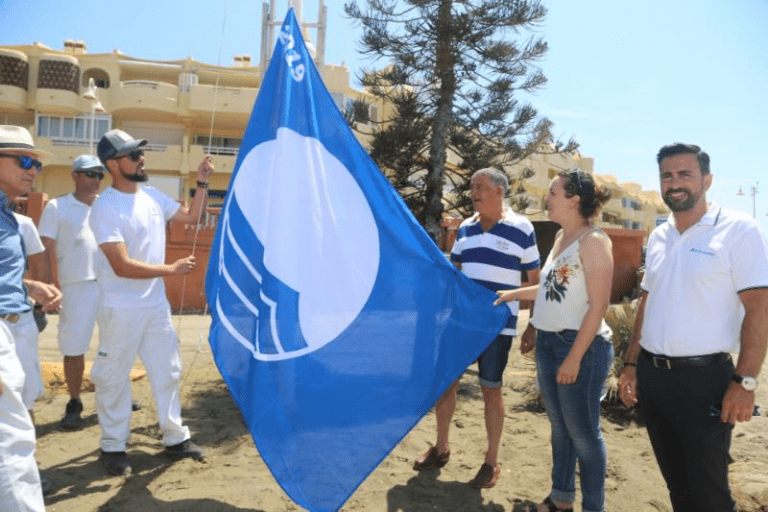 El alcalde Víctor Navas y la concejala Encarnación Cortés  izan las banderas azules en el  de Benalmádena