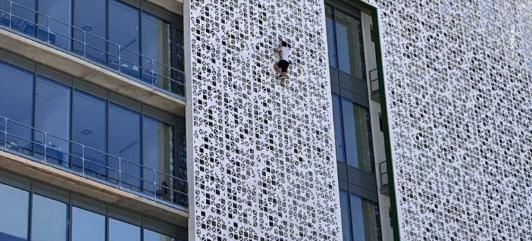 Un hombre escala la fachada del ayuntamiento de Estepona de siete plantas de altura